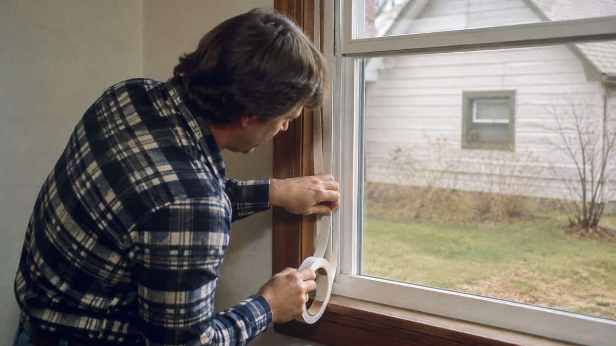 Household Skills Worth Relearning That Could Save You Thousands 9 Homeowner weatherproofing a window