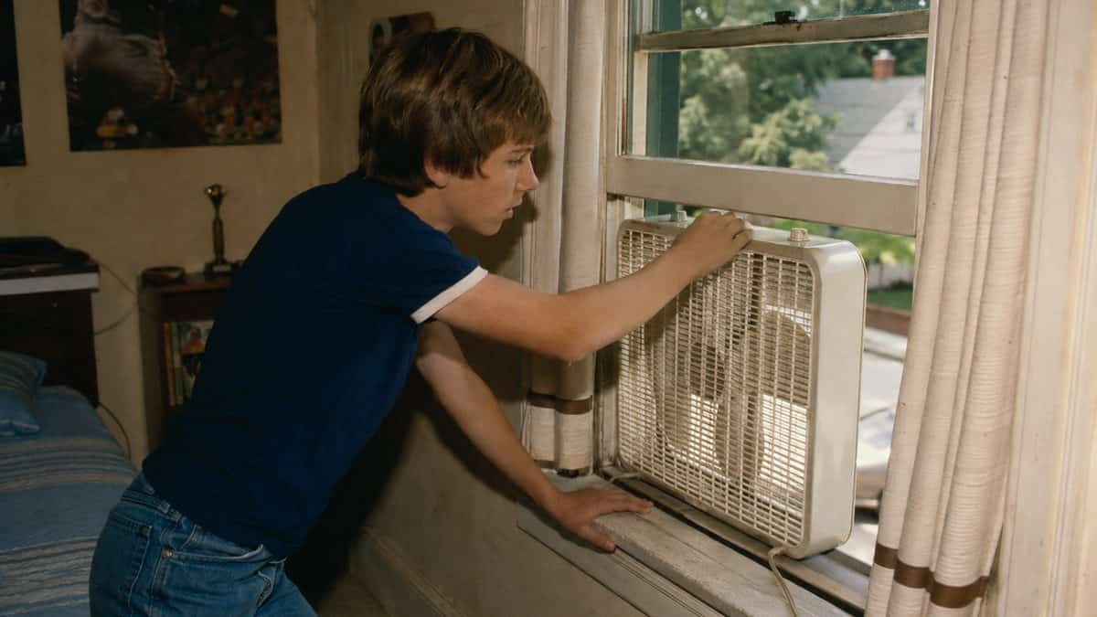 Someone adjusting a window or box fan