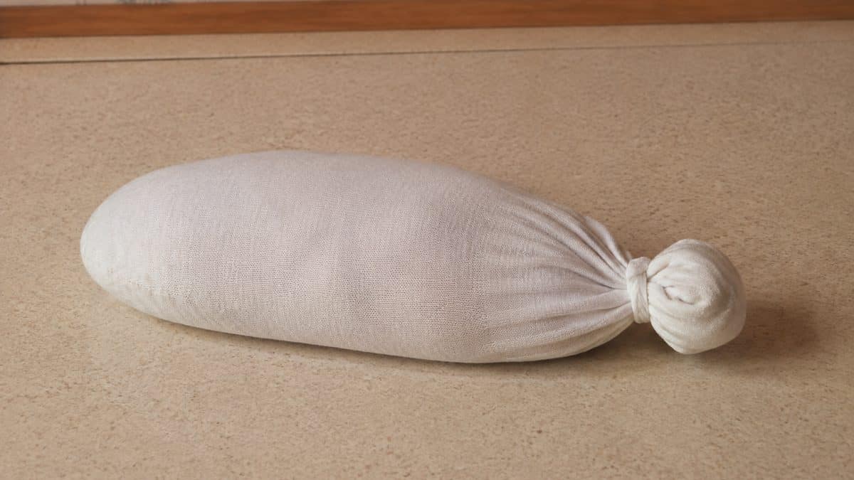 15 Basic Life Hacks from Grandma That Still Beat Modern Solutions 13 Real photograph of a single white tube sock tied at the end, filled with rice, resting on a kitchen counter.