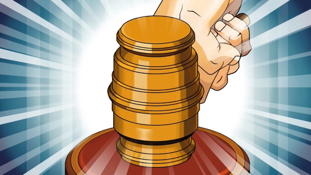 Hand placing a coin on a stack of coins with a gavel in the background.