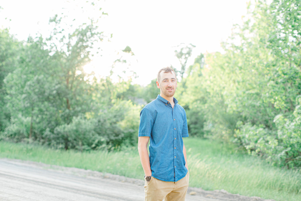 Groom to Be - posing during Engagement Session  Sunset - Natural Posing for Photo Session - Couples Photo Session Fun - Fun on the Farm - Farm Engagement Session - Blue and Brown Engagement Session Inspiration - Natural Engagement Session Posing - Ideas for what to wear for Engagement Photography, Modern Engagement Session Inspiration Wardrobe Ideas. Unsure of what to wear for your engagement photos, we've got you! Romantic brown with black leggings for Summer Engagement in Almonte. Grey Loft Studio is Ottawa's Wedding and Engagement Photographer for Real couples, showcasing photos that are modern, bright, and fun.