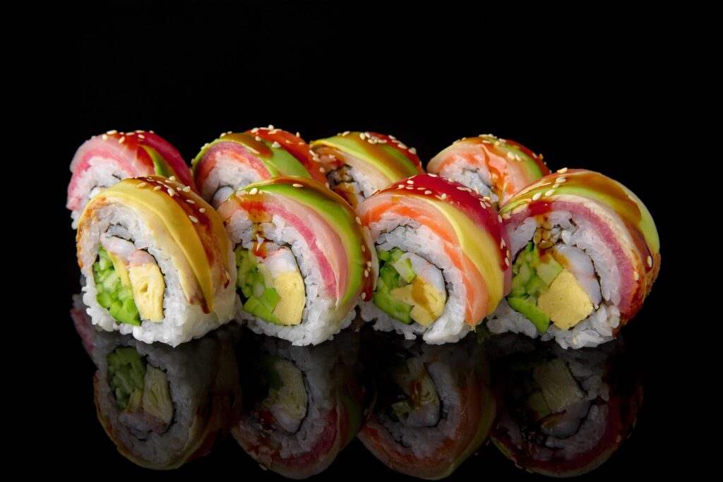 Assorted sushi rolls with vibrant colors on black background.