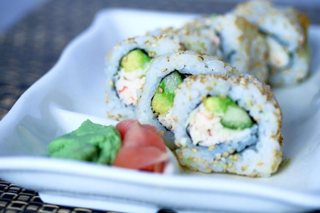 Delicious sushi rolls with avocado and crab on a white plate.