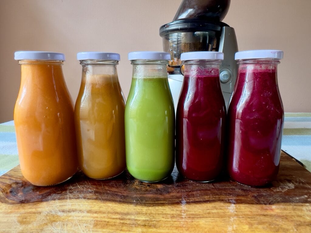 Vibrant juice bottles with colorful homemade juices on a wooden surface, ideal for blood pressure mo.