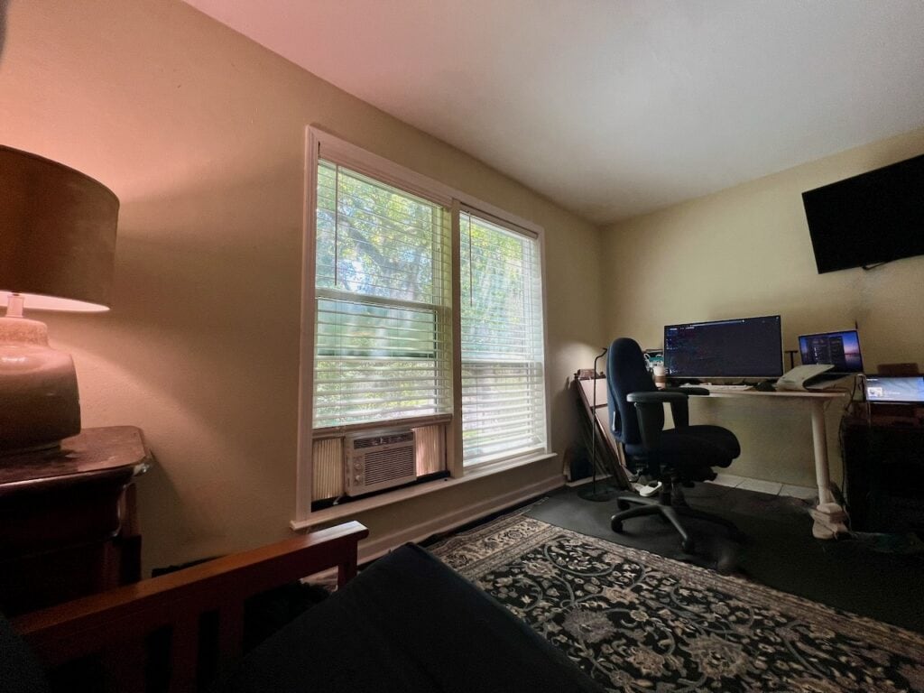 Home office with desk, computer, and window view of trees.