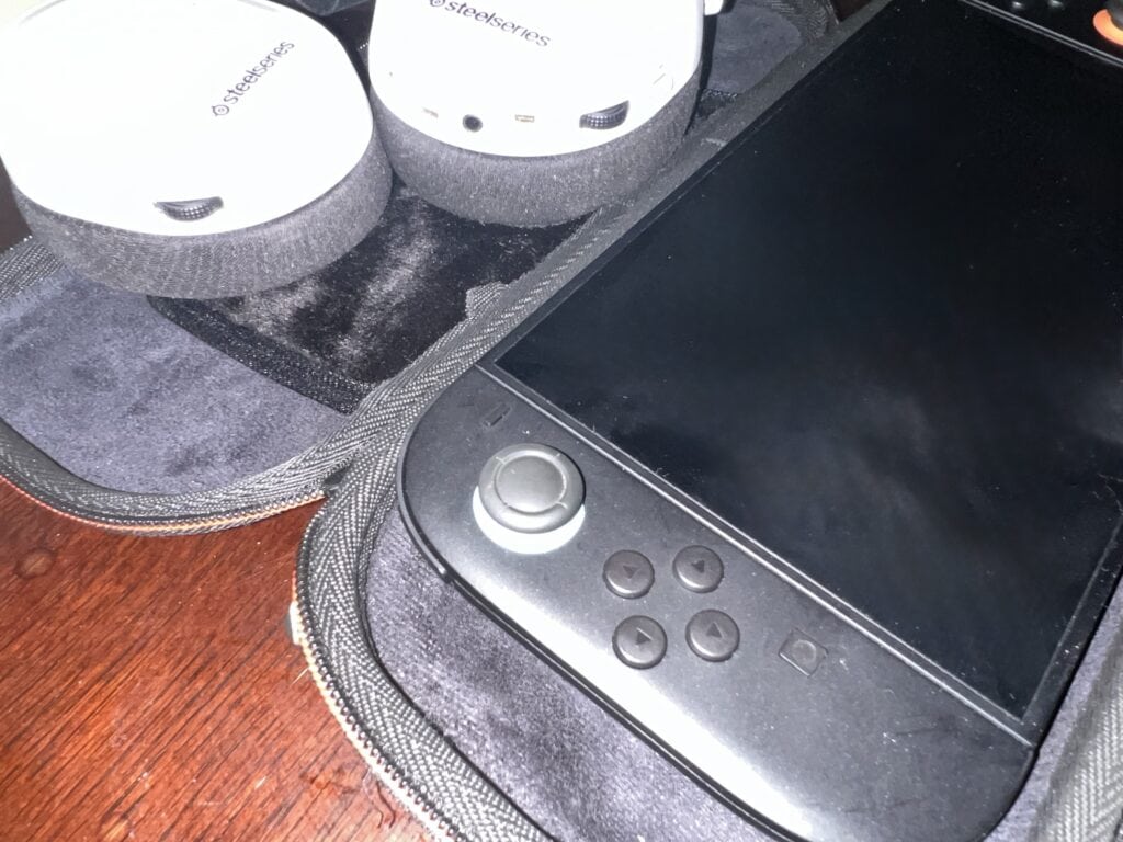 Wireless audio devices and portable gaming console on desk.