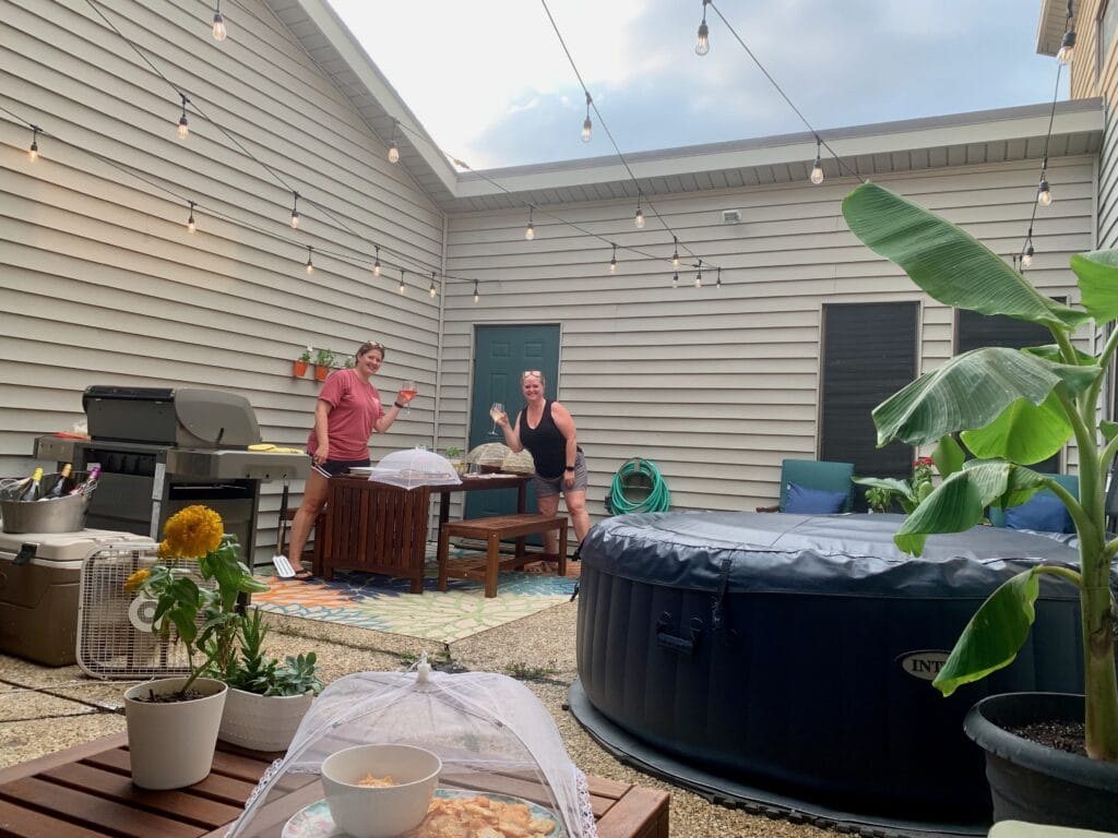 Outdoor patio with hot tub, string lights, and two women enjoying the space.
