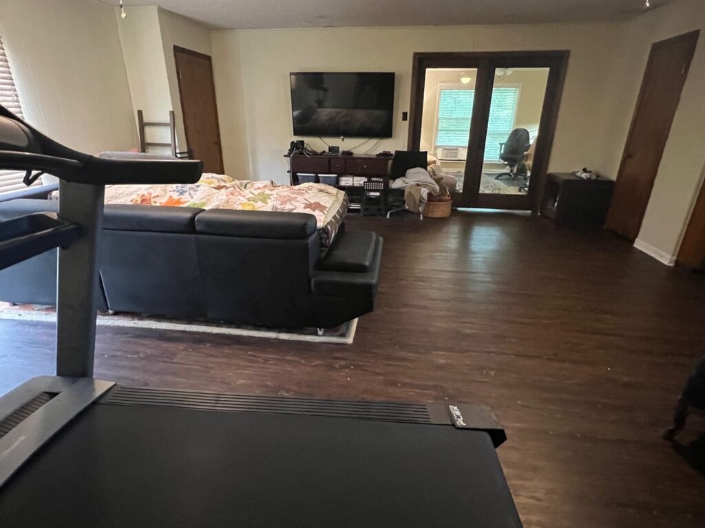 Spacious living room with TV, sofa, and balcony access.