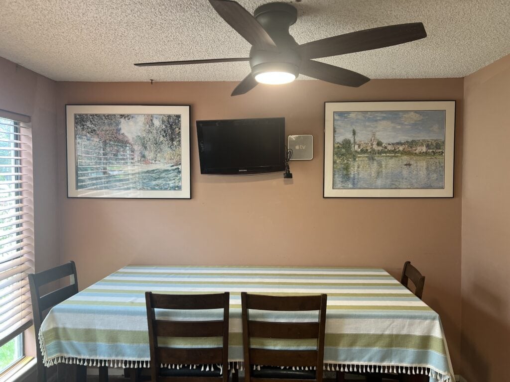 Contemporary dining room with striped tablecloth, wall art, and wall-mounted TV.