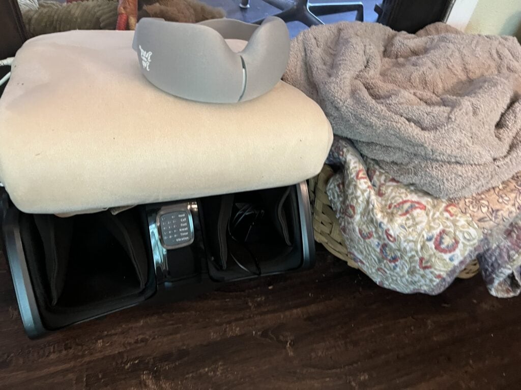 Gray ergonomic car neck pillow on beige cushion with blanket nearby.