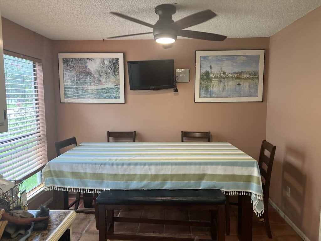 Cozy dining room with a table, chairs, wall art, and a wall-mounted TV.