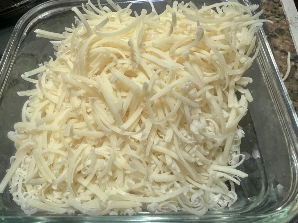 Close-up of shredded cheese in a glass container for recipes.