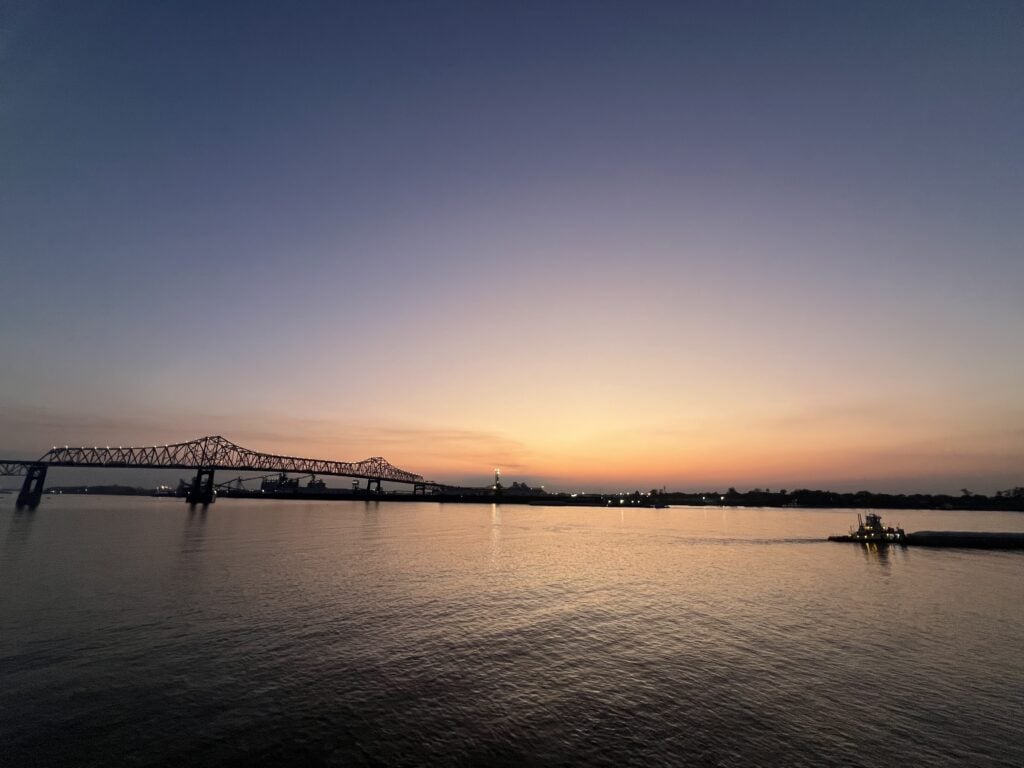Beautiful sunset over river with bridge and boat at dusk.