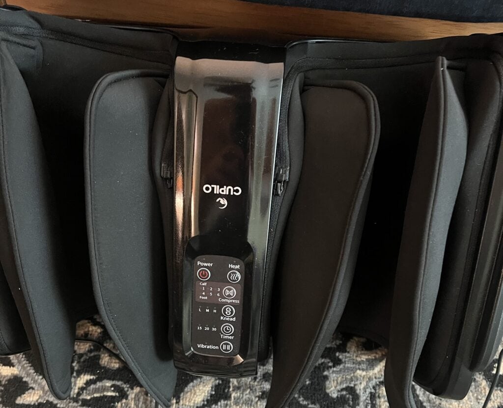 Portable leg massager with black carrying case and control panel.