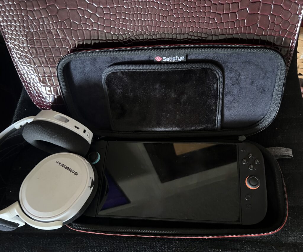 Portable gaming device with headphones and carrying case for travel.