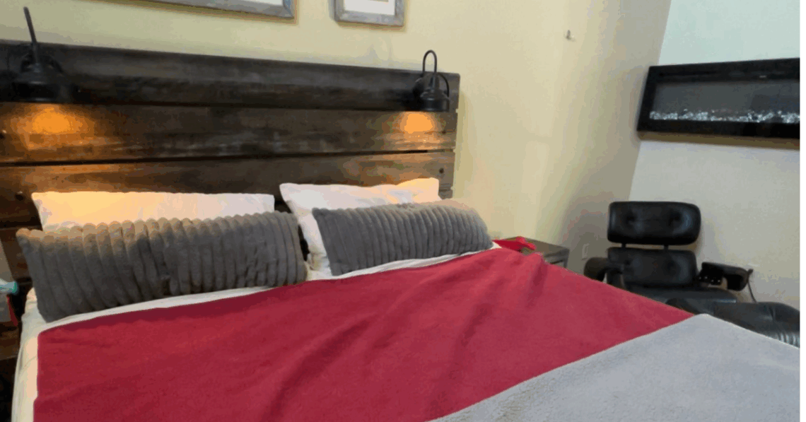 Cozy modern bedroom with a wooden headboard, gray pillows, and a red and gray bedspread. Perfect for.