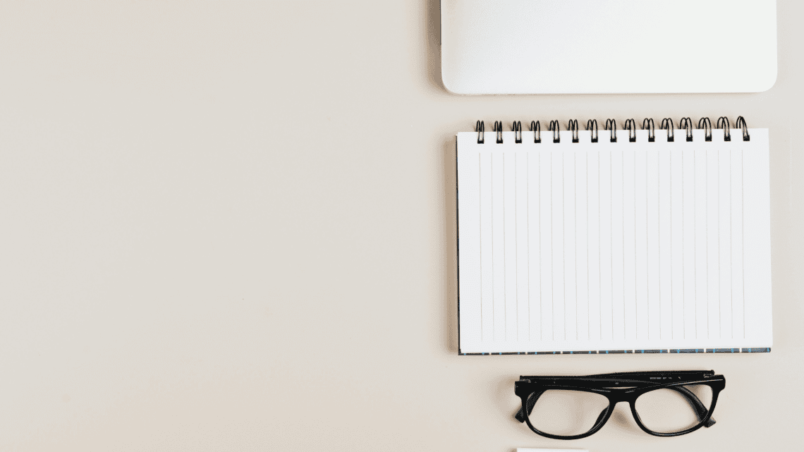 Notepad, glasses, and laptop on desk for FSA eligible items planning.