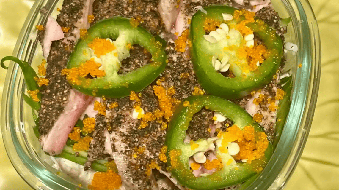 Close-up of jalapeño slices topped with fish roe and chopped nuts.