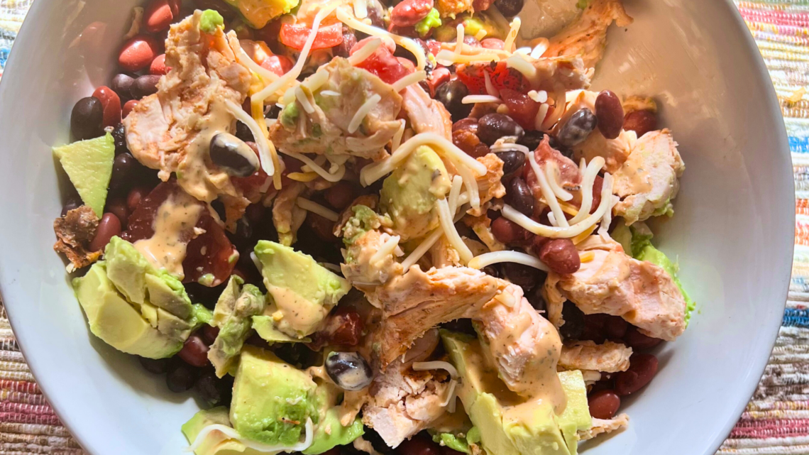Fresh no-cook lunch protein bowl with chicken, black beans, avocado, and cheese.