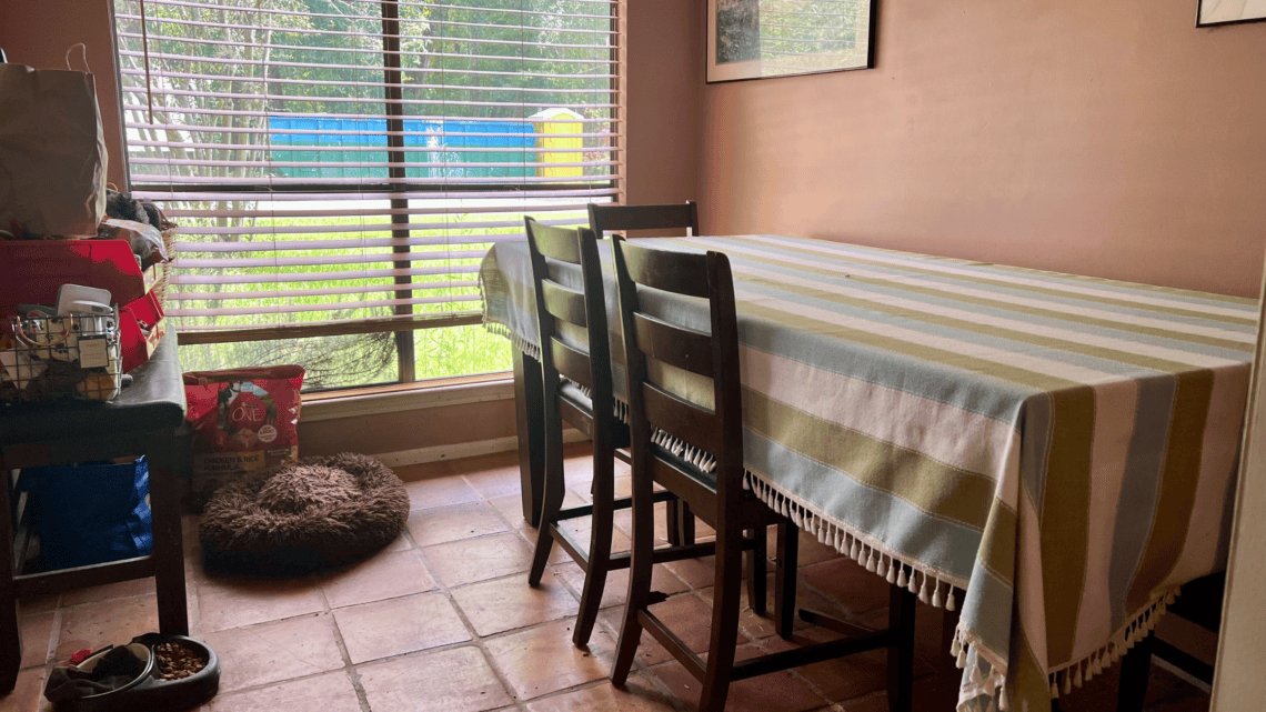 Bright dining room with striped tablecloth and large window.