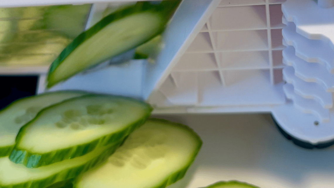 Fresh cucumber slices next to a food processor for healthy meal prep.