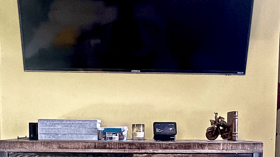 Modern home decor setup with TV and decorative items on wooden shelf.