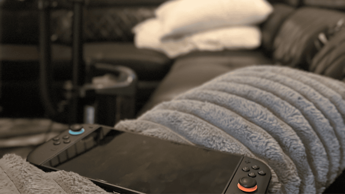 Nintendo Switch console on a cozy couch with blanket and pillows.