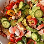 Colorful cucumber, crab, and avocado summer salad in a white bowl.
