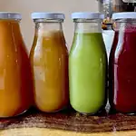 Assorted fresh juice bottles with vibrant colors on a wooden surface.