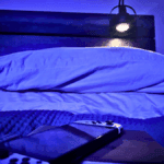 Comfortable gaming setup with pillows and remote in a dimly lit room.