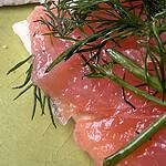 Close-up of cured salmon garnished with dill on a textured ceramic plate