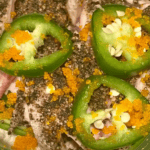 Close-up of jalapeño slices topped with fish roe and chopped nuts.