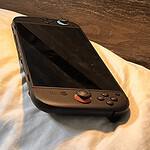 Handheld gaming console on a bed for cozy night-in gaming sessions.