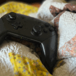 Nintendo Pro Controller resting on a colorful quilt bed.