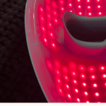 Red LED face mask for skincare with bright red lights and black interior.