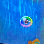 Vibrant bubble floating in a digital game environment with blue and green hues.