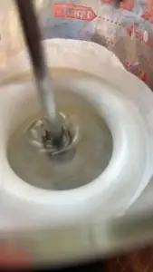 Close-up of the push whisk mixing ingredients in a kitchen setting.