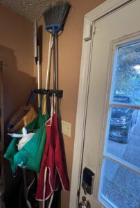 Cleaning tools and supplies hanging near a door for organization.