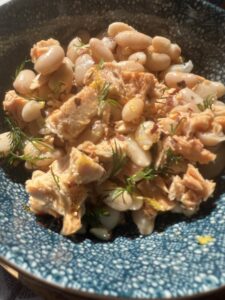 Fresh white bean and tuna salad with herbs, served in a decorative blue bowl.