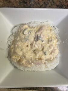 Close-up of creamy chicken and mushroom sushi on white plate.
