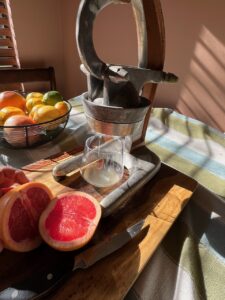 Juicer with fresh citrus fruits on a wooden cutting board.