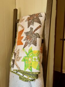 Vibrant patchwork quilt with animal and geometric patterns on a wooden chair.