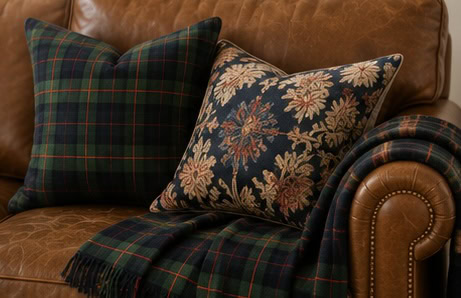 Tartan and floral cushions on a leather sofa for cozy home decor.