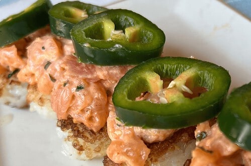Delicious crispy rice bites topped with spicy salmon and jalapeño slices, perfect for quick sushi sn.