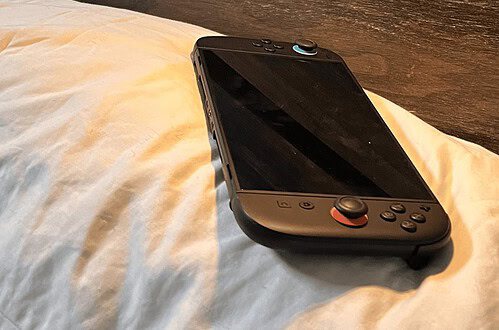Handheld gaming console on a bed for cozy night-in gaming sessions.