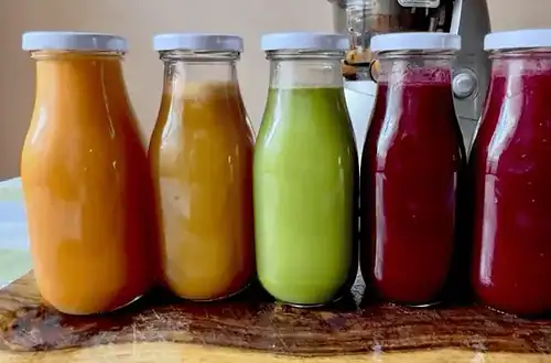 Assorted fresh juice bottles with vibrant colors on a wooden surface.