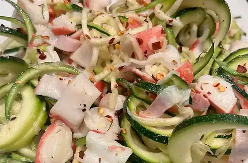 Fresh zucchini noodles with crab meat and spices for a healthy dish.