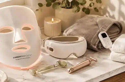 CurrentBody skin care devices and mask on marble countertop in spa setting.