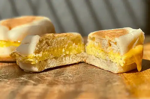 Close-up of a breakfast sandwich with egg and melted cheese.