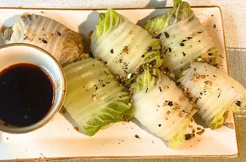 Lettuce wraps with dipping sauce on a rectangular plate for healthy eating.